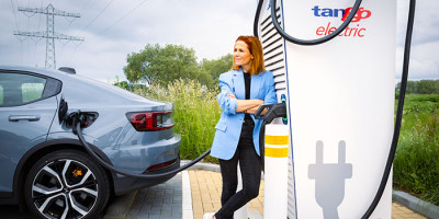 vrouw leunt tegen Tango electric laadpaal