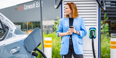 Vrouw staat naast EV wagen bij Tango electric laadstation