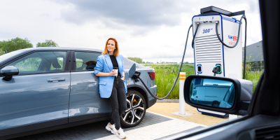 Vrouw leunt tegen elektrische wagen bij Tango electric